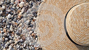 Close-up of a straw hat lies on the background of small sea shells on the beach,copy space.The concept of vacation,vacation,summer