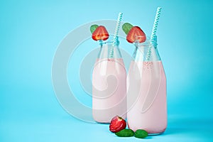 Close-up strawberry smoothie or milkshake in glass jar with berries on blue background.