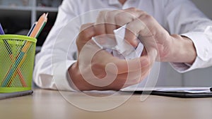 Close-up stressed businessman in anger destroys business papers and bangs his fist on the table. Workplace aggression