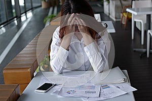 Close up stressed frustrated young Asian business woman covering face with hands on the desk in office