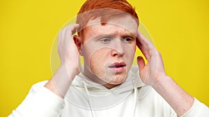 Close-up of stressed man having panic attack. Portrait of young redhead Caucasian guy having nervous breakdown at yellow