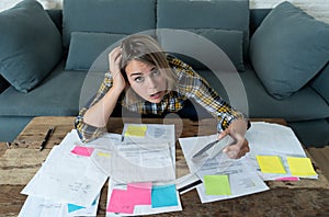 Close up of stressed and overwhelmed young woman paying bills and managing home finances