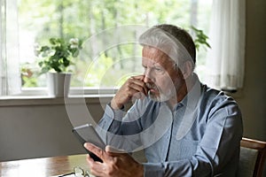 Close up stressed unhappy mature man looking at phone screen