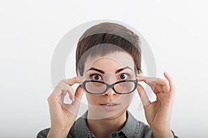 Close up of strict surprised young funny female teacher or student in glasses isolated on white background, looking over