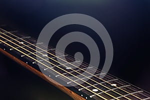 Close-up of strings on the fretboard of an acoustic guitar