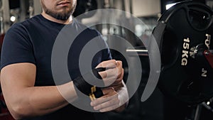 Close-up of a strong boxer man putting on red straps and getting ready to fight, prepare for workout training