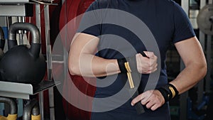 Close-up of a strong boxer man putting on red straps and getting ready to fight, prepare for workout training