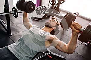 Close up of a strong man doing push ups with the dumbells. He is consentrated only on doing that exercise and on nothing