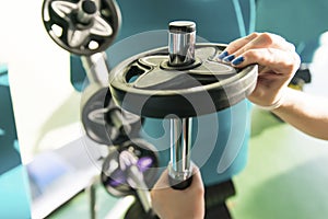 Close-up of strong woman preparing for workout training and adding extra weight plate for barbell