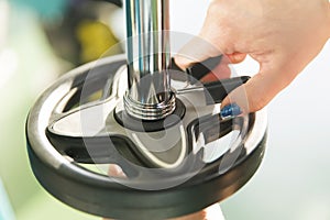 Close-up of strong woman preparing for workout training and adding extra weight plate for barbell