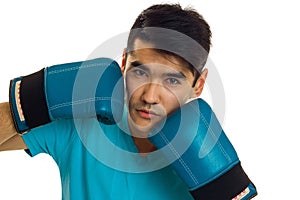 Close up of strong young brunette man in blue gloves practicing boxing and looking at the camera isolated on white