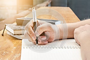 Close up of student hand writing on book with pen