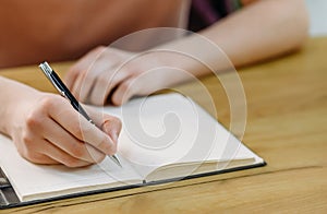 Close-up of a student& x27;s hand holding a pen and making notes in a notebook