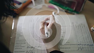 Close-up of the student`s hand. The student holds a pen in his hand