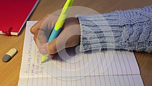 Close-up of a student's hands in a notebook write in English.