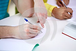 Close up of students hands writing to notebooks
