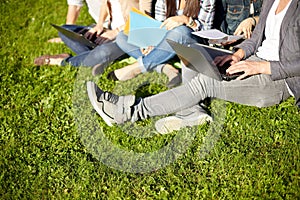 Close up of students with laptop sitting on grass