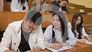 Close-up of students writing a lecture. The girl writes off the test work from a classmate. A group of students is