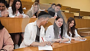 Close-up of students writing a lecture. The guy writes off the test work from a classmate. A group of students is