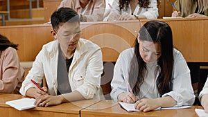 Close-up of students writing a lecture. The guy writes off the test work from a classmate. A group of students is