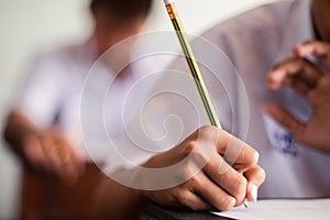 Close up Students writing and reading exam answer sheets exercises in classroom of school with stress