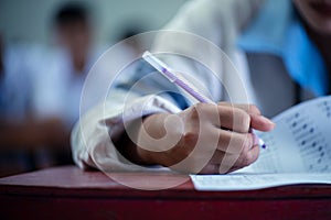 Close up Students writing and reading exam answer sheets exercises in classroom of school with stress