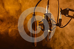 Close up studio condenser microphone on stand and anti-vibration mount. Live recording with colored lights background. Side view.