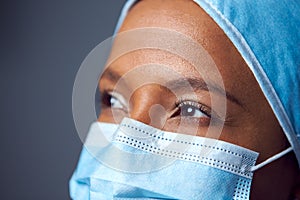 Close Up Studio Portrait Of Female Surgeon Wearing Scrubs And Face Mask