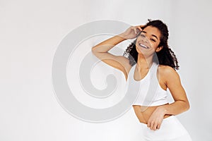 Close up studio portrait of happy beautiful athletic girl of african ethnicity in white top and leggings