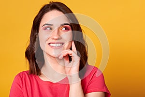 Close up studio portrait of pretty lovely charming lady looking away, keeps hand under chin, trying to understand or remember