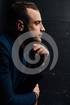 Close-up Studio portrait of young man face hand-touch , holding chin, looking.