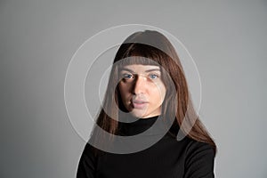 Close up studio portrait of a young woman against plain grey background