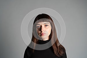 Close up studio portrait of a young woman against plain grey background