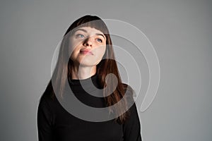 Close up studio portrait of a young woman against plain grey background