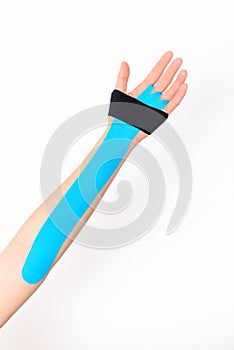 Close up studio shot of a female arm with kinesio tape, isolated over white background. Kinesiology, physical therapy.