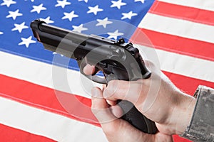 Close up studio shot of gun in hand with flag on background - United States of America