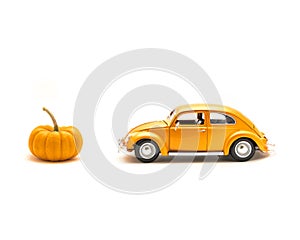 Close-up studio shot small orange toy car with mini pumpkin isolated on white