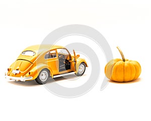 Close-up studio shot small orange toy car with mini pumpkin isolated on white