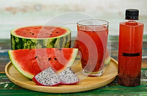 Close up studio shot of sweet delicious healthy sliced watermelon and fresh ripe cold dragon fruit juice in glass placed on wood