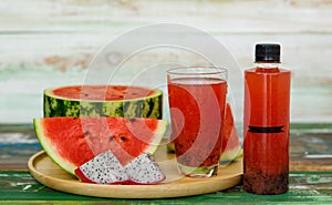 Close up studio shot of sweet delicious healthy sliced watermelon and fresh ripe cold dragon fruit juice in glass placed on wood