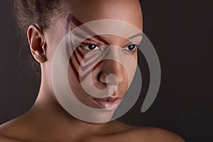 Close up studio shot of the young woman of the mulatta with abstract make up on dark background