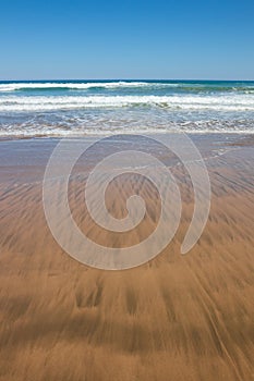 Close up study of waves and sand patterns at Makorori Beach, near Gisborne, New Zealand