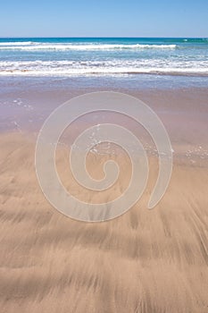 Close up study of waves and sand patterns at Makorori Beach, near Gisborne, New Zealand