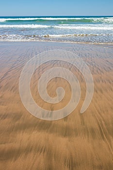 Close up study of waves and sand patterns at Makorori Beach, near Gisborne, New Zealand