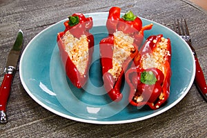 Close up of stuffed red paprika bell peppers with sheep feta cheese seasoned with spicy chili on wood table