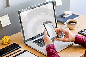 Close up of stylish composition with businessman, mock up laptop screen, cup of coffee, plants and office supplies in modern home