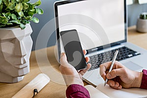 Close up of stylish composition with businessman, mock up laptop screen, cup of coffee, plants and office supplies in modern home