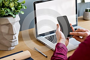 Close up of stylish composition with businessman, mock up laptop screen, cup of coffee, plants and office supplies in modern home