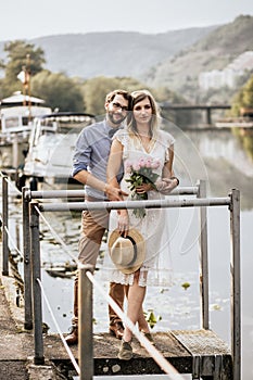 Close up of stylish couple in embrance on quay with nature background