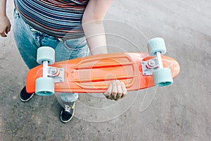 close up stylish girl carrying the penny board in the summer city